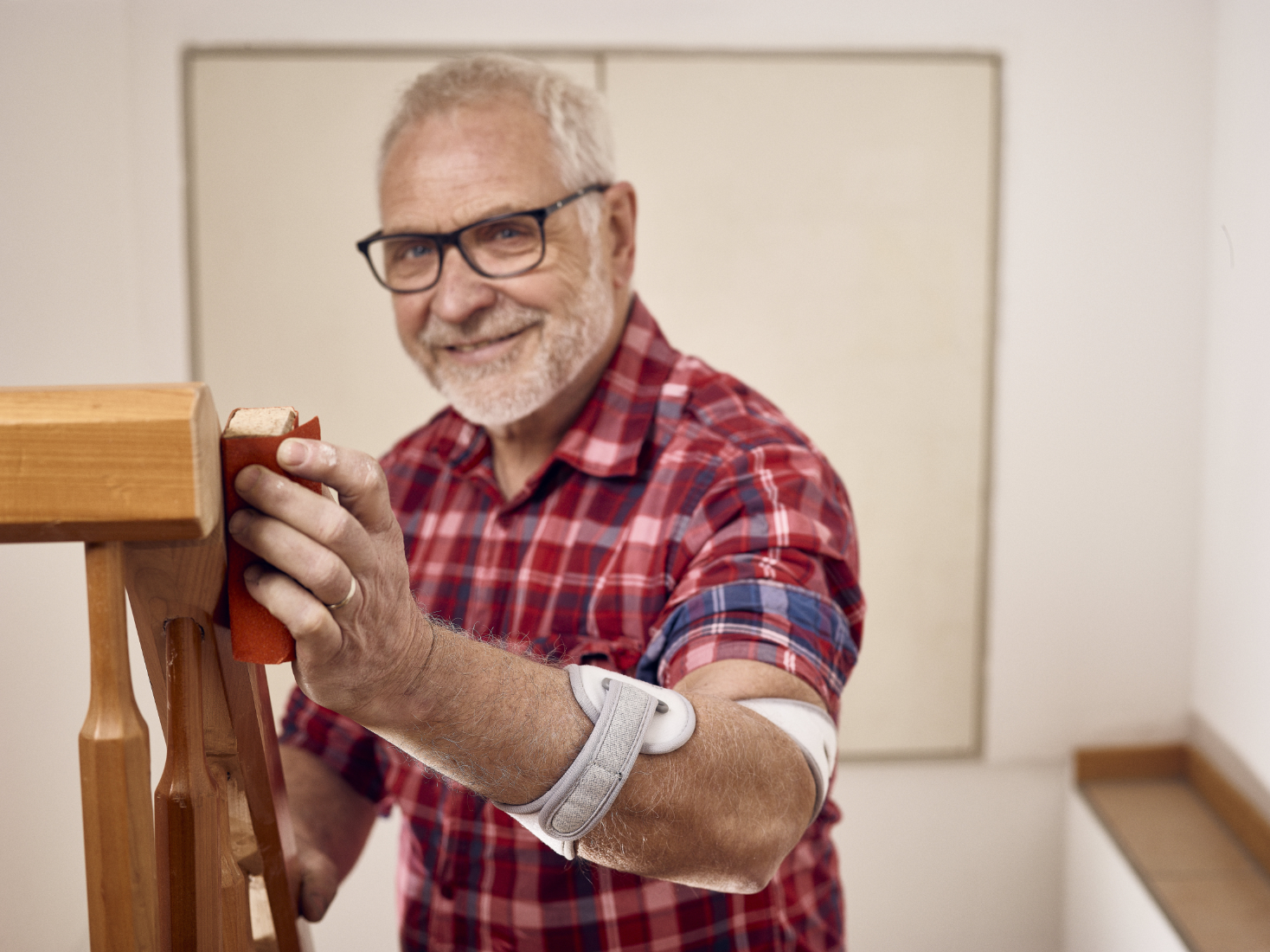Masalo Manschette MED - schmerzfrei arbeiten bei Epicondylitis  Älterer Herr mit Masalo Manschette schleift ein Treppengeländer ab