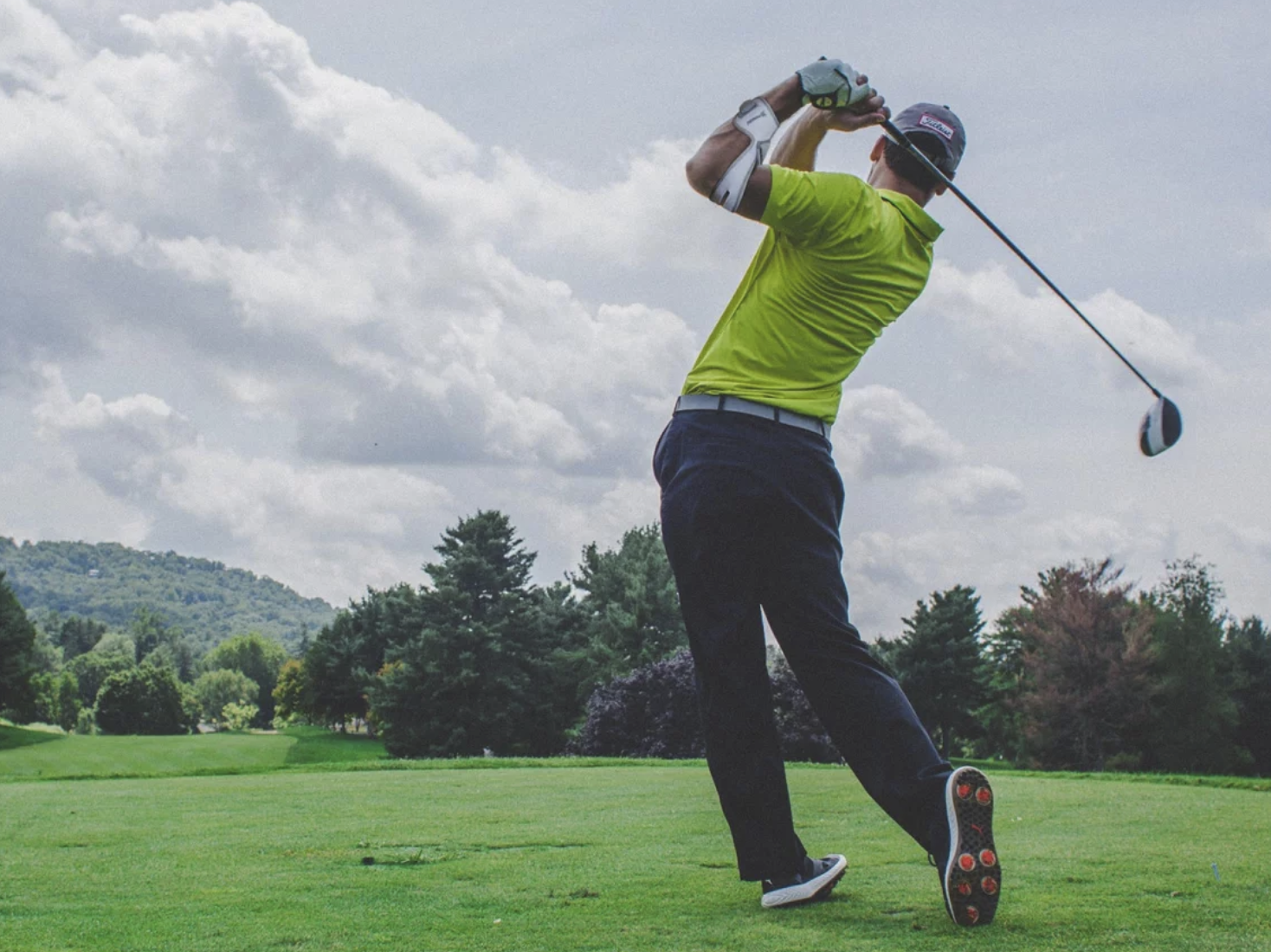 Masalo Manschette tragender Mann spielt Golf auf dem Golfplatz.